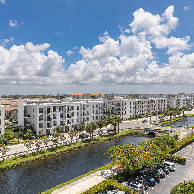 Modern apartments beside canal under cloudy sky.